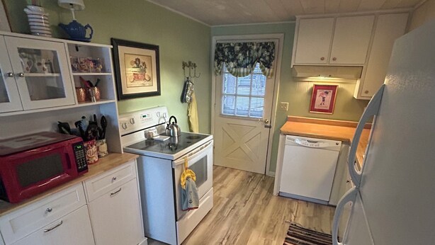 A compact kitchen with white cabinetry, a microwave, a stove, and a refrigerator. - Lakefront Retreat Near Wisconsin Dells:  Kayak use Private Beach and Treehouse (Friendship)