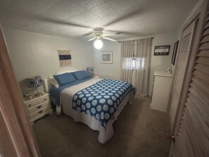 A bedroom with a bed, a nightstand, a dresser, a ceiling fan, and a sign on the wall. - Lakefront Retreat Near Wisconsin Dells:  Kayak use Private Beach and Treehouse (Friendship)