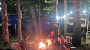 A group of people sitting around a campfire on a wooden deck at night. - Lakefront Retreat Near Wisconsin Dells:  Kayak use Private Beach and Treehouse (Friendship)