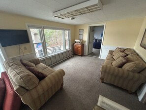 A living room with two couches, a television, and a door leading to a bedroom. - Lakefront Retreat Near Wisconsin Dells:  Kayak use Private Beach and Treehouse (Friendship)