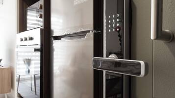 A modern kitchen with a stainless steel refrigerator, a built-in oven, and a digital lock on the door.