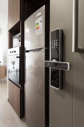 Cocina moderna con refrigerador de acero inoxidable, horno empotrado y cerradura digital en la puerta.