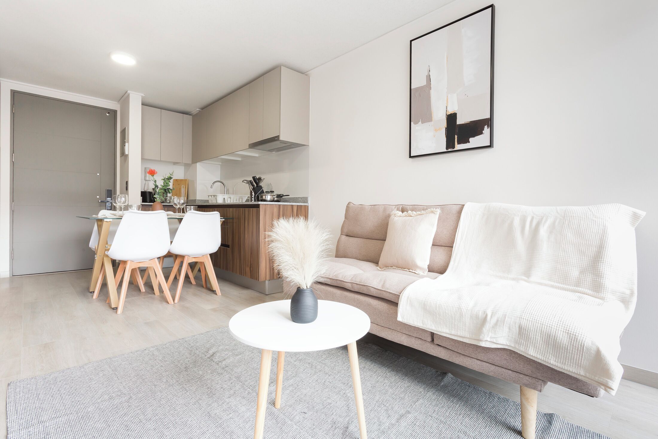 A modern living room with a sofa, a dining area with chairs, and a kitchen in the background.