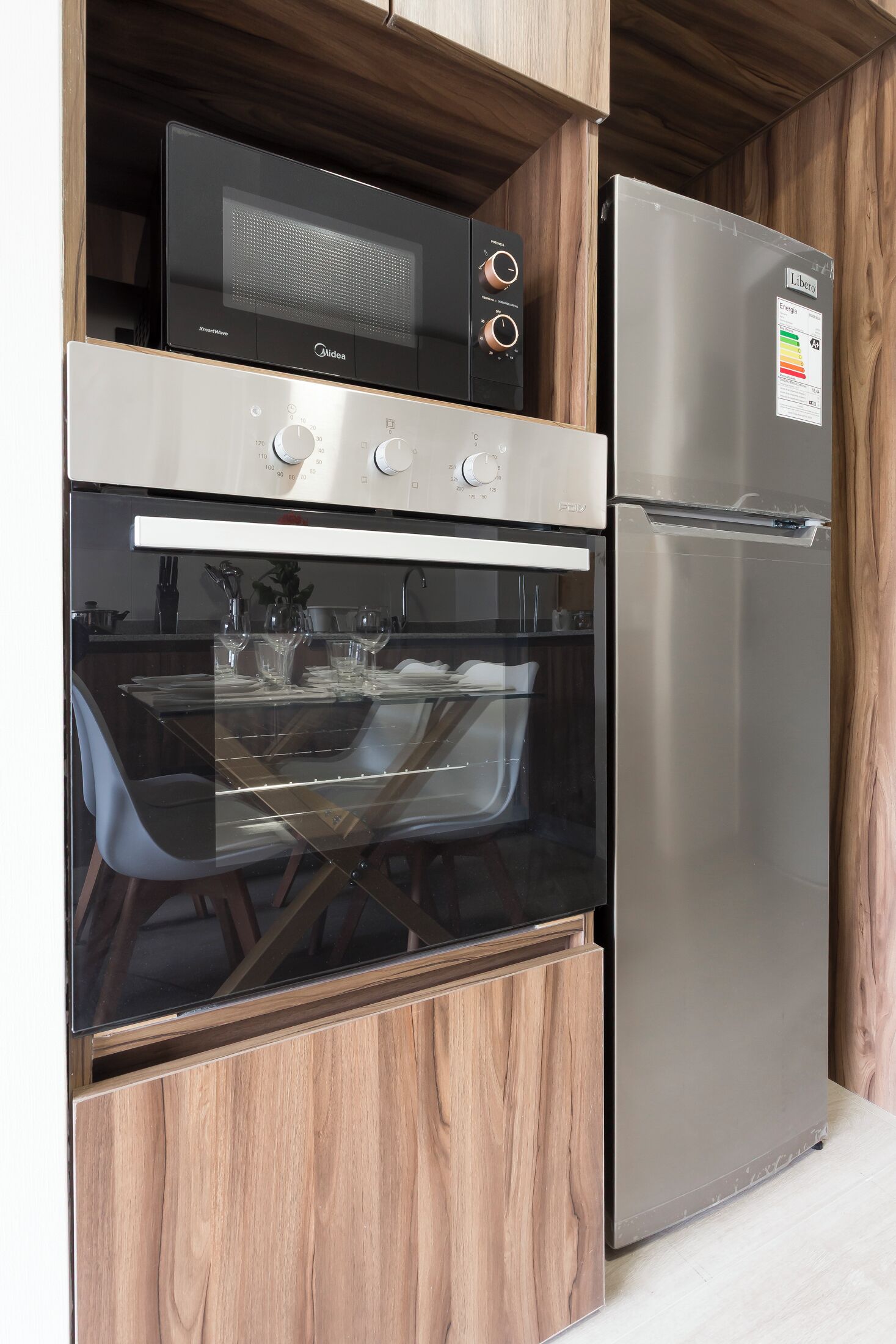 A kitchen with a built-in oven and a stainless steel refrigerator.