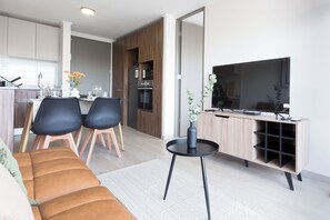 A modern living room with a sofa, two chairs, a coffee table, and a TV on a stand.