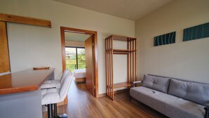A modern room with a wooden desk, a grey sofa, and a wooden shelf unit. - Narin Retreat (Zeta trece)