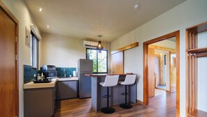 A modern kitchen with a central island, bar stools, and a view of the outdoors. - Narin Retreat (Zeta trece)