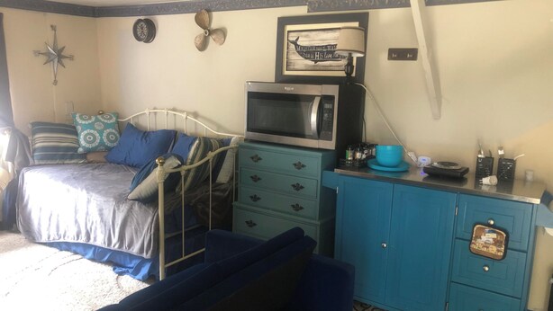 Un dormitorio con una cama, un aparador, un microondas y un adorno en la pared.