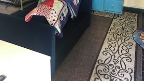 Un dormitorio con cama, cómoda, microondas y un detalle decorativo en la pared.