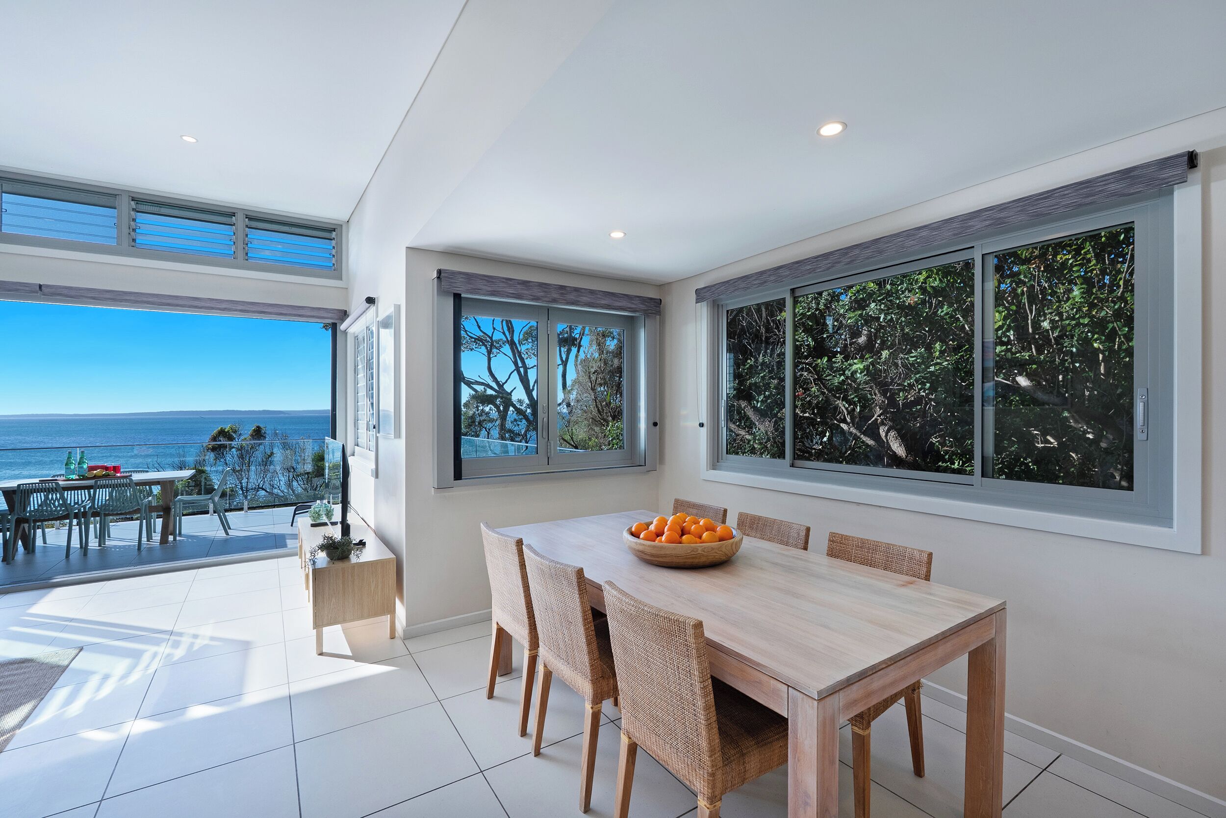 A modern dining area with a view of the sea, a large window, and a table with chairs.