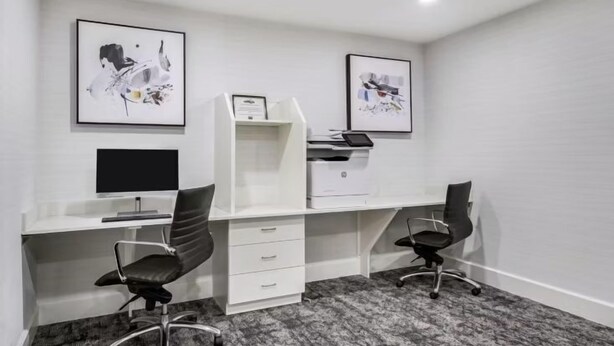 A modern office space with two desks, chairs, a printer, and framed artwork on the walls. - Accessible 2BR Suite | Roll Shower & Hot Breakfast (Maumee)