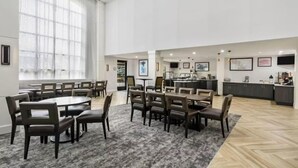 A conference room with a large table and chairs, a kitchen area with cabinets and appliances, and a large window with curtains. - Accessible 2BR Suite | Roll Shower & Hot Breakfast (Maumee)