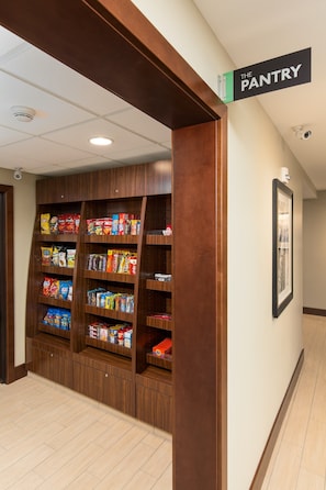 A hallway with a wooden pantry shelf stocked with snacks and beverages.
