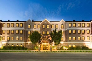 A multi-story hotel with a central entrance, large windows, and a stone facade.