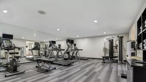 A gym with treadmills, weight machines, and a mirrored wall.
