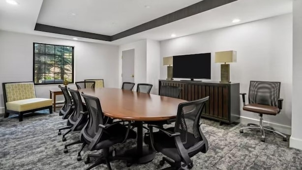 A conference room with a large table, chairs, a television, and a window.