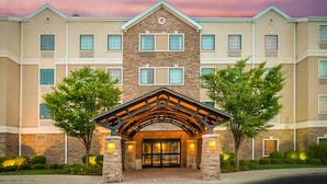 A multi-story hotel with a stone facade, a covered entrance, and a landscaped front yard.