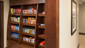 A hallway with a wooden pantry shelf stocked with snacks and beverages.