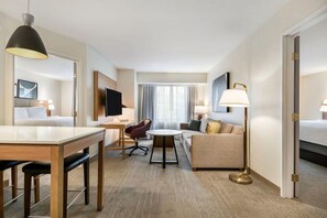 Una habitación de hotel con una cama, un escritorio, una silla, un sofá, un televisor y una lámpara.