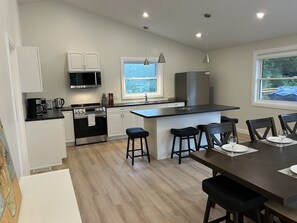 A modern kitchen with a central island, white cabinetry, and a dining area with a table and chairs.