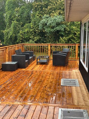 A wooden deck with outdoor furniture, a glass table, and a metal vent. - Maitland Inlet Cottage — Where Goderich Sunsets, Beach Days, and Waterviews Meet (Goderich)