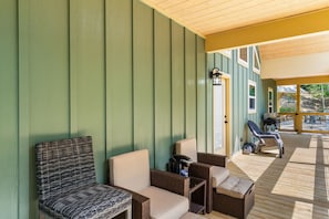 A covered outdoor seating area with wicker furniture and a grill. - Escape to Pop's Porch, a brand-new mountain cabin (Brasstown)
