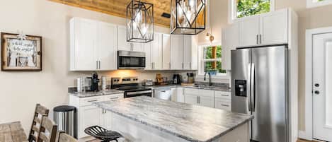Una cocina moderna con gabinetes blancos, electrodomésticos de acero inoxidable y una encimera de mármol.