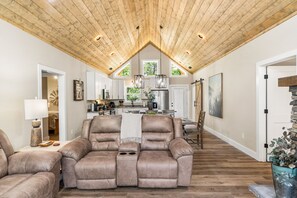A spacious living area with a high ceiling and a dining area in the background. - Escape to Pop's Porch, a brand-new mountain cabin (Brasstown)