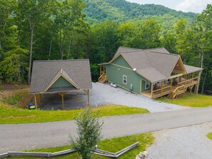 A cabin with a covered porch and a separate garage, surrounded by a forested area. - Escape to Pop's Porch, a brand-new mountain cabin (Brasstown)