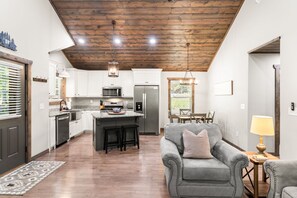 A modern kitchen with white cabinets, stainless steel appliances, and a wooden ceiling. - Peaceful Seasons – A Cozy Mountain Retreat with Modern Comforts (Murphy)