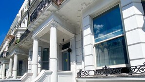 A building with white facades, multiple windows, and balconies with black railings. - Cozy Flats Near Olympia and Westfield (London)