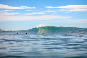 Eine große Welle im Meer mit mehreren Surfern im Wasser.