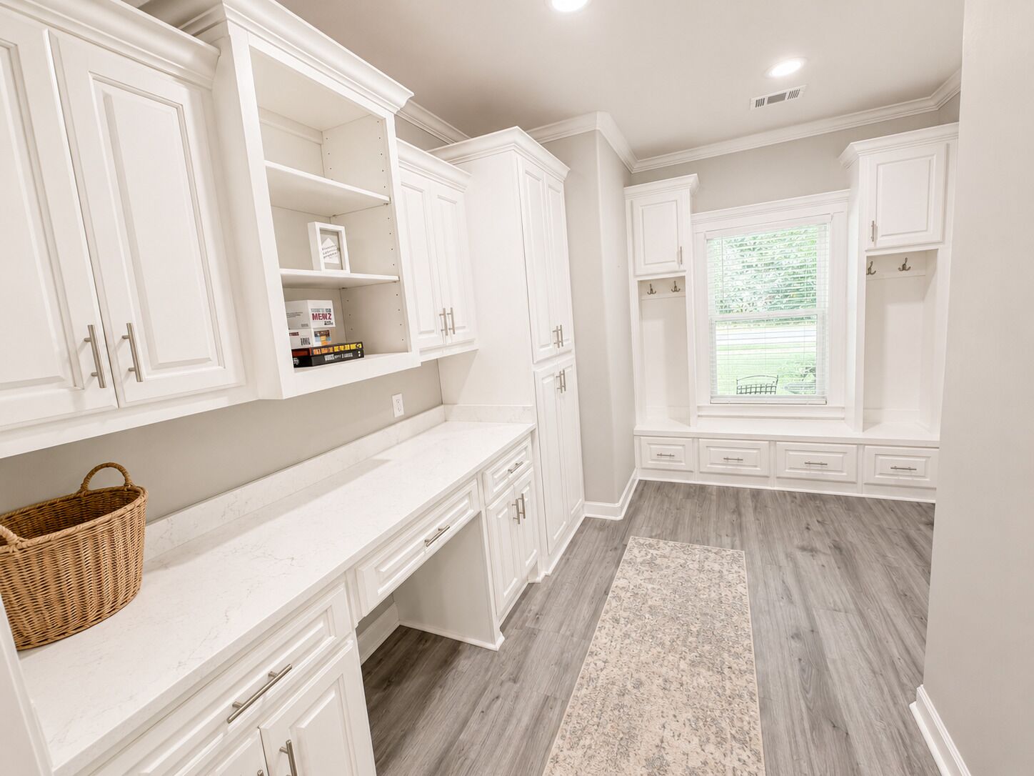 A kitchen with white cabinetry, a marble countertop, and a window with blinds.