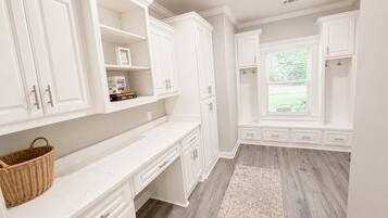 A kitchen with white cabinetry, a marble countertop, and a window with blinds.