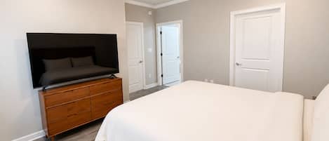 A bedroom with a bed, a dresser, a television, and a ceiling fan.