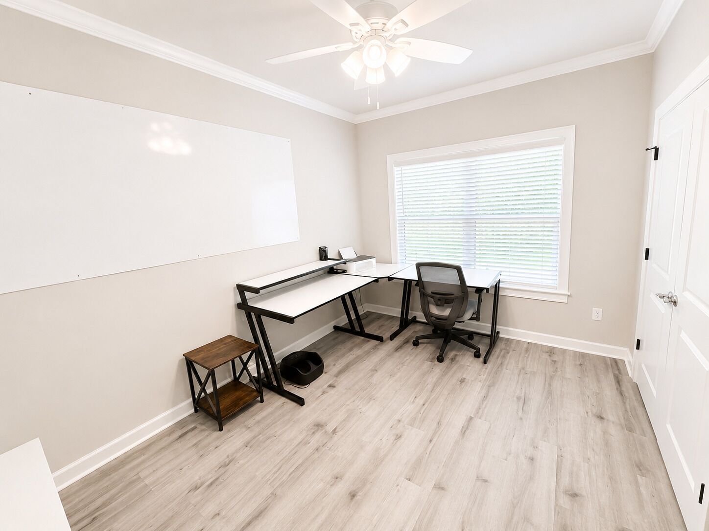 A room with a desk, chair, whiteboard, and a window with blinds.