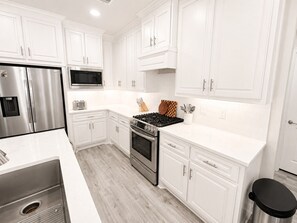 A modern kitchen with white cabinetry, stainless steel appliances, and a black countertop.