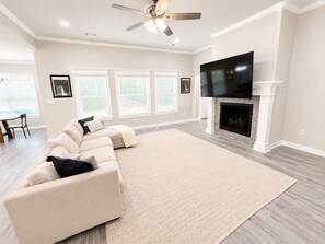A spacious living room with a sectional sofa, a fireplace, and a flat-screen TV.