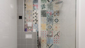 A bathroom with a shower, toilet, and a patterned wall. - A comfortable family room with secure parking near the city center. (Subotica)