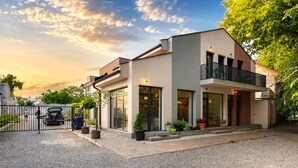 A modern two-story building with a gated entrance, potted plants, and a clear sky. - A comfortable family room with secure parking near the city center. (Subotica)