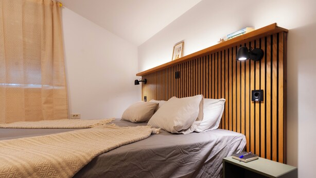 A bedroom with a bed, bedside table, and a wall-mounted shelf. - A comfortable family room with secure parking near the city center. (Subotica)