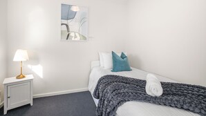 A hotel room with a bed, a nightstand, a lamp, and a wall art piece. - Rest and Roam - A Executive Sepal Stay (Perth)