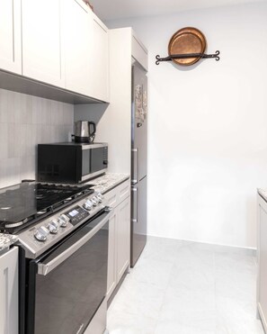 A modern kitchen with stainless steel appliances, white cabinetry, and a tiled backsplash. - Ana Pellicer House (Ciudad de México)