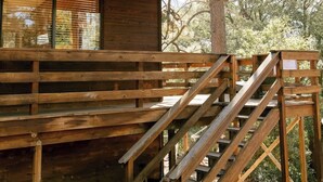 Eine Holzhütte mit Schornstein, einer Holzterrasse und einer Treppe zum Eingang.