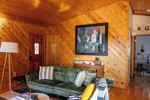 A cozy room with a green sofa, a lamp, and a painting on the wall. - Idyllwild Cabin w/ Mountain Views & Deck (Idyllwild-Pine Cove)