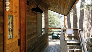 Eine Holzhütte mit Veranda, einer Tür mit Buntglasfenster und einer Bank.