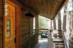 Eine Holzhütte mit Veranda, einer Tür mit Buntglasfenster und einer Bank.