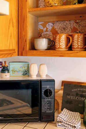 A kitchen with a microwave, a timer, and a tea tin. - Idyllwild Cabin w/ Mountain Views & Deck (Idyllwild-Pine Cove)