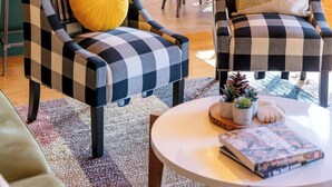 Ein gemütliches Wohnzimmer mit karierten Sesseln, einem runden Couchtisch und einem Bücherregal.