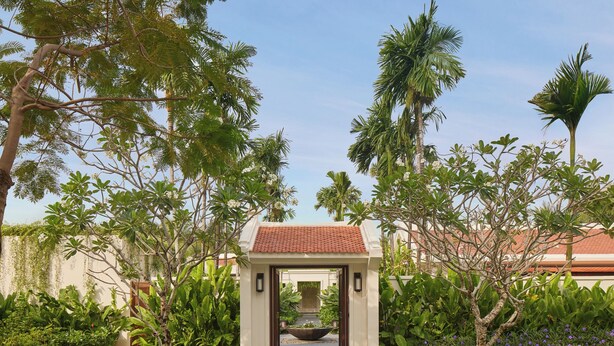 A pathway leading to a building with a tiled roof, surrounded by lush greenery and palm trees. - Park Hyatt Phu Quoc (Phu Quoc)